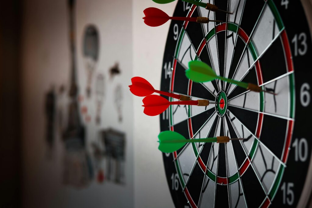A close-up view of a dartboard with red and green darts hitting the bullseye, symbolizing precision and achieving goals, relating to the focus keyword "How to Build a Website"—emphasizing careful planning and targeted success.